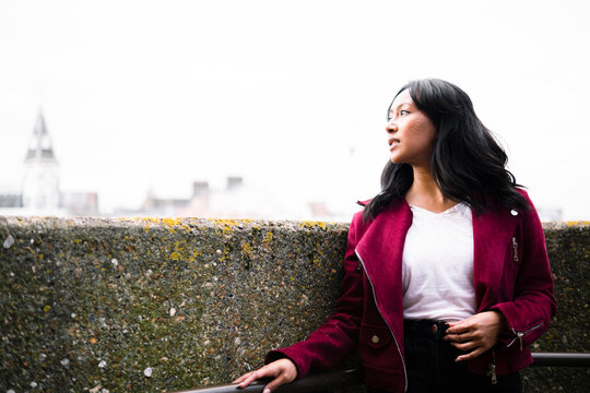 Thoughtful woman standing near wall under clear sky