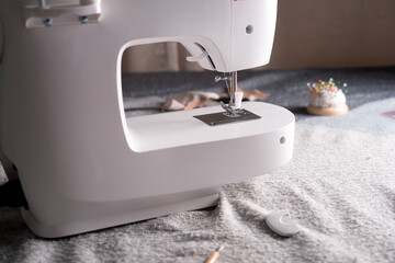 close-up of a sewing machine amidst a fabric setting, with a focus on its needle and a pin cushion,...