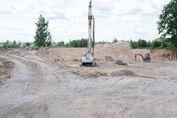 expansive construction site with large drilling machine and excavator amidst earthy landscape with...