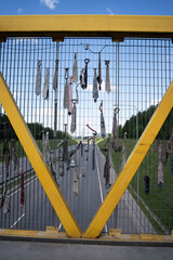 ties hang loosely through the grid railing of a yellow pedestrian overpass with a highway and...