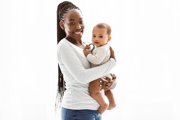 Maternal Love. Positive smiling young African American mother with long afro braids holding cute...