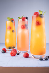 refreshing tall glasses of vibrant orange and pink cocktails garnished with fresh mint,...