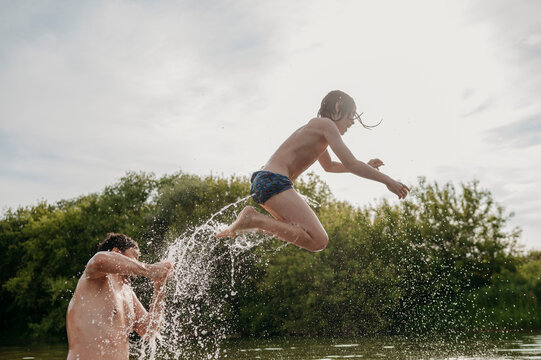 Father with son jumping in water on sunny day
