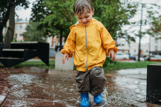 Happy boy splashing water in puddle at park