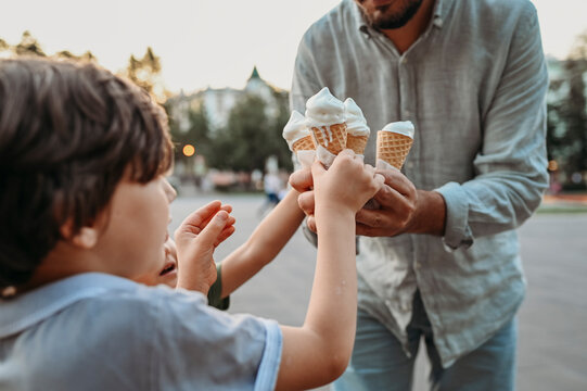 Father giving ice cream cones to sons