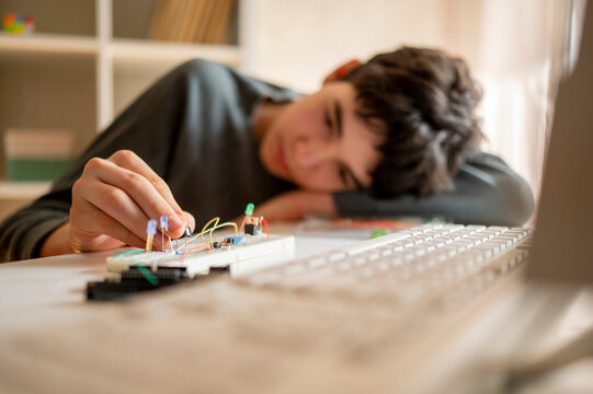 Boy adjusting electrical micro controller near keyboard at home