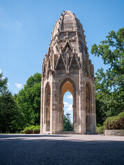 Fototapeta premium Gothic tower in Sad Janka Kráľa park, Bratislava. Originally part of a Franciscan church from the 15th century, now a historic monument surrounded by trees.