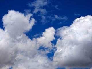 Fluffy white clouds appearing against a bright blue sky during a sunny afternoon in late spring