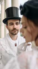 Man in top hat gazing at woman in blurred foreground in vintage setting. Concept of historical...