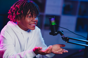 Energetic youth vlogger recording content with microphone setup in a neon-lit studio, expressing...