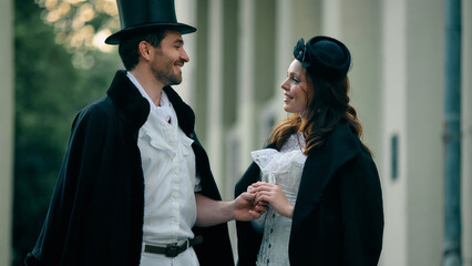 Smiling couple in vintage costume holding hands outdoors. Concept of romantic book cover,...
