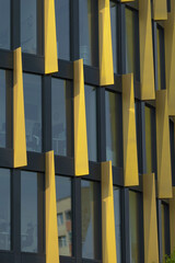 This image showcases a closeup view of a large commercial building that features numerous windows and is adorned with striking yellow columns