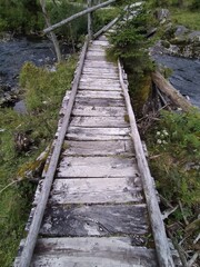 Fototapeta premium Old Wooden Footbridge Over Mountain Stream