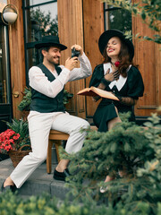 Retro styled man with vintage camera sitting on bench and taking picture of emotional woman....