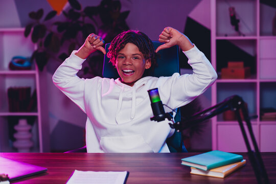 Positive blogger streaming podcast with microphone at night in neon studio environment capturing audience engagement