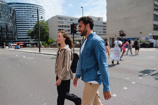 Happy man and woman walking together on street in city