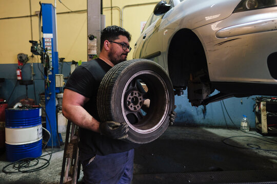 Mechanic removing tire from car at workshop