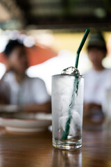 A glass of water with ice cubes and a green straw, refreshing drink cold beverage clear liquid...