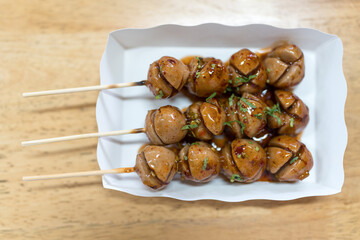 Grilled meatballs with chili and sweet sauce on paper tray, top view
