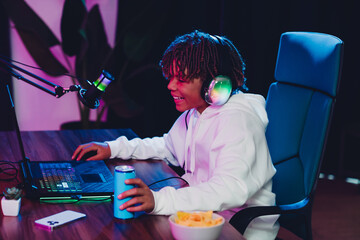Young male gamer streaming online at night using a professional microphone in a vibrant neon-lit room