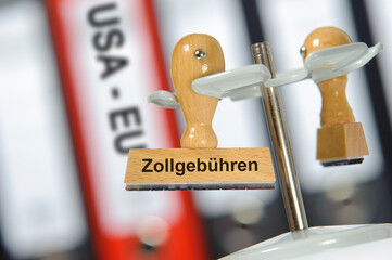 Ein Holzstempel ist beschriftet mit dem Aufdruck Zollgebühren als Symbol für den Zollstreit und...