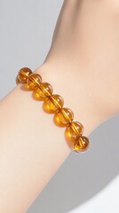 Elegant Amber Bracelet: An exquisite amber bracelet gracefully adorns a wrist, its warm, inviting glow captivating the eye and adding a touch of luxury to any ensemble. 