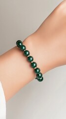 Elegant Emerald Bracelet: A close-up shot of a person's wrist adorned with a captivating emerald bracelet. The rich, dark green of the gemstones contrasts beautifully with the delicate skin.