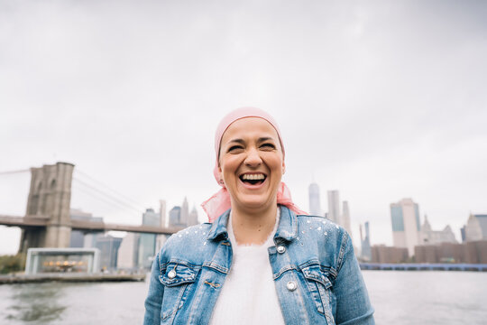 Portrait of laughing woman with cancer bandana at Brooklyn Bridge in New York, USA