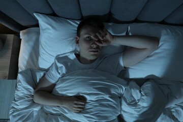 Frustrated man suffering from insomnia in bed indoors, top view