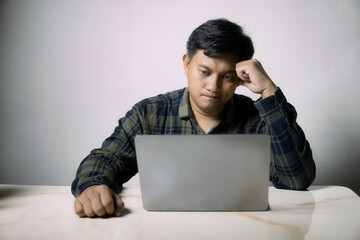 A focused man in a plaid shirt intently works on his laptop, deep in thought or concentration. Ideal for themes of remote work, study, or problem-solving.