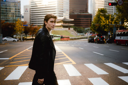 Model in leather jacket crossing a street in Seoul at dusk