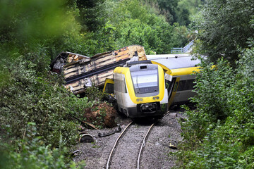 A train accident scene showing derailed and damaged carriages lying motionless.