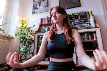 Brunette woman meditating in a cozy home office setting