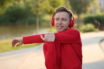 Smiling sportsman in headphones doing morning exercise outdoors. Healthy lifestyle