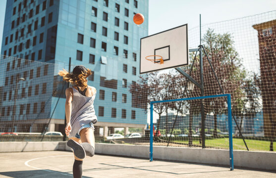 Young woman aiming at basketball hoop