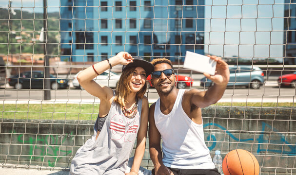 Young couple taking selfie at basketball court
