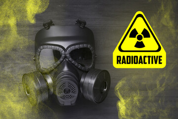 Radiation threat. Gas mask, radioactive sign and smoke on grey wooden background, top view