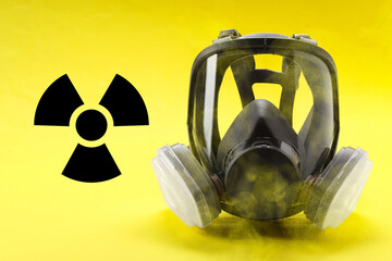 Radiation threat. Gas mask, radioactive sign and smoke on yellow background