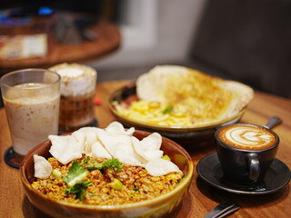 Fusion of Asian fried rice, pasta, and three types of coffee served on a wooden café table. Perfect cozy meal for lunch or dinner time.
