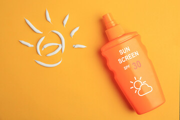 Sunscreen in bottle and sun made of sun protection cream on orange background, top view