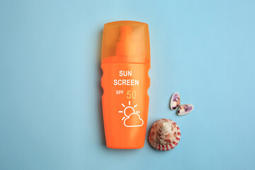 Sunscreen in bottle and seashells on pastel blue background, top view. Sun protection product