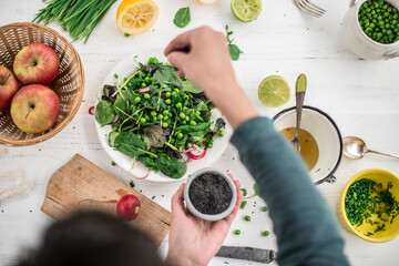 Hand preparing salad seasoning with black sesame