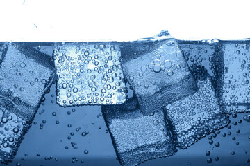 Soda water with bubbles and ice cubes in glass, closeup