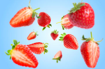 Yummy fresh strawberries swirling in air against blue background