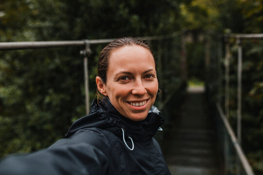Smiling mid adult woman on suspension bridge during rainy day