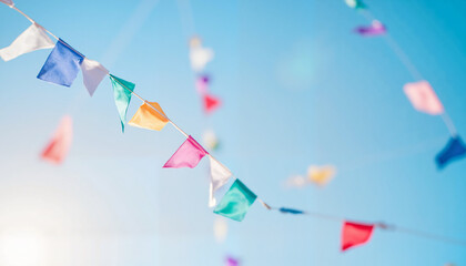 Colorful festive pennant flags hanging against a bright blue sky  