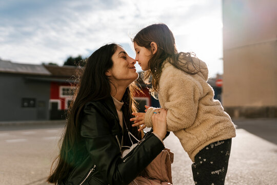 Daughter rubbing nose with mother while standing on road