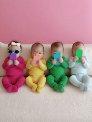 Babies in colorful matching outfits sitting on white couch holding smartphones creating playful commentary on modern digital childhood and technology use, copy space. 
