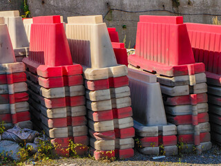 Stacked red and white safety barriers ready for road construction work outdoors.