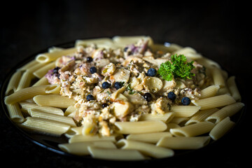 ready to eat - noodles with boletus, parsley and blueberries, served on a black plate